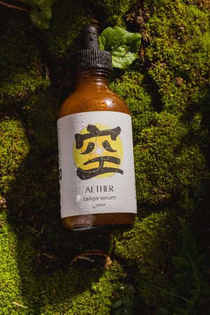 Bottle of Aether tallow serum on a mossy background