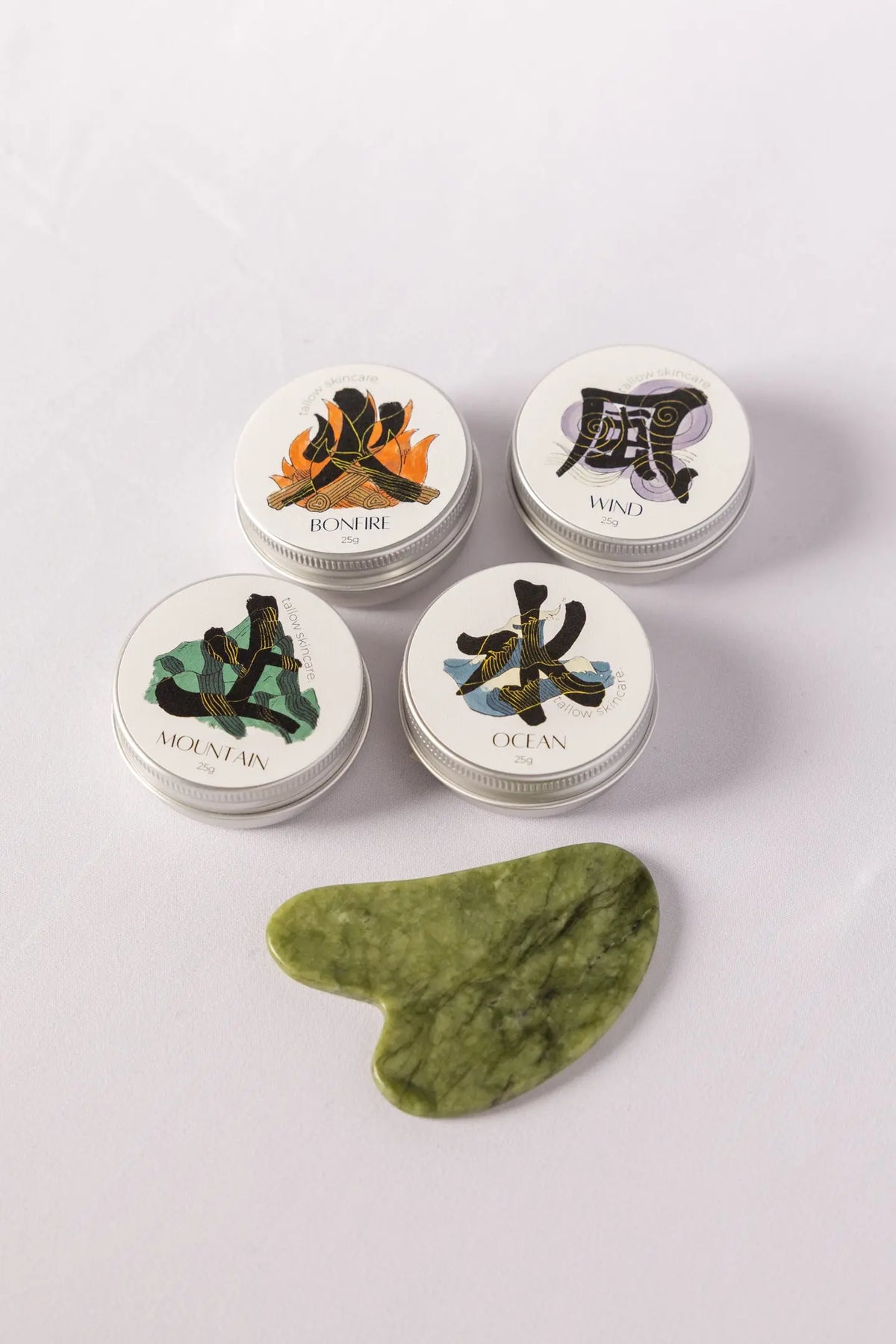 Four small tallow containers with lids featuring nature-themed designs on a light gray background.