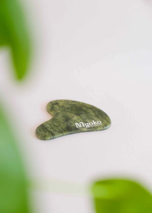 Green gua sha tool with 'Myoko' branding on a white background