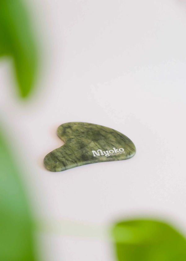 Green gua sha tool with 'Myoko' branding on a white background